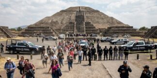 Visitors walking towards the Pyramid of the Sun at Teotihuacan with police vehicles nearby