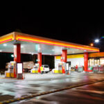 A gas station illuminated at night with fuel pumps and a convenience store
