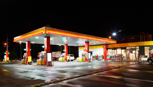 shutterstock_747071503.jpg A gas station illuminated at night with fuel pumps and a convenience store