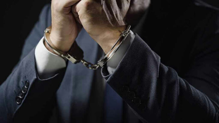 Man in suit wearing handcuffs.