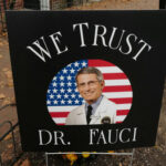 yard sign with a portrait of a man in a lab coat before a U.S. flag