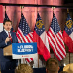 Man speaking at Florida Blueprint event with American flags.