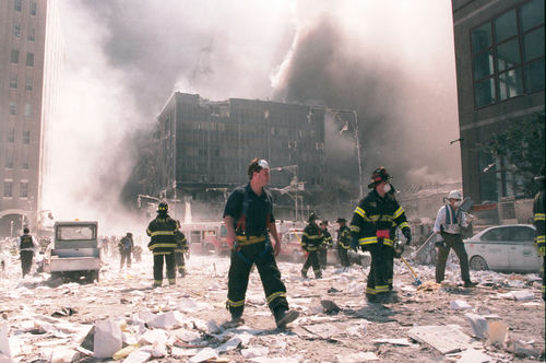 shutterstock25159549-2jpg Firefighters walking through debris near a heavily damaged smoking building