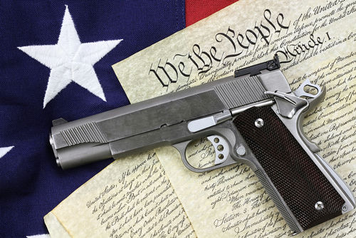shutterstock_129482747-2- A handgun placed on top of the U.S. Constitution and an American flag