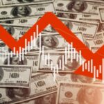 A downward trend graph overlaying a background of hundred-dollar bills