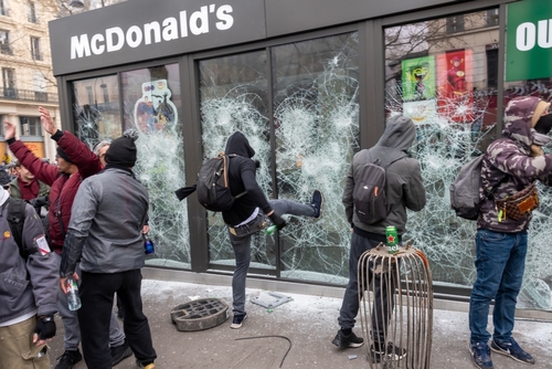 shutterstock_2279898999.jpg Protesters vandalizing a McDonald's restaurant with broken windows