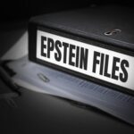 A black binder labeled 'EPSTEIN FILES' with papers and office supplies nearby