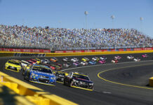Stock cars racing on a track with packed stands.