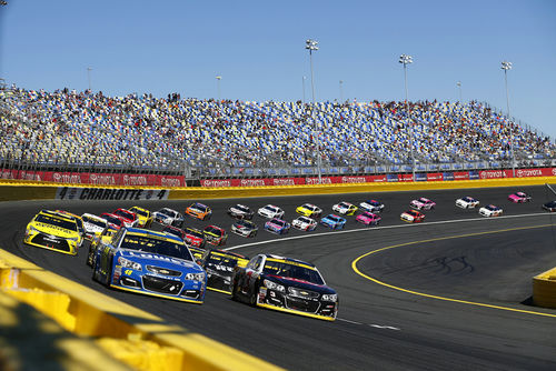 shutterstock_497557876 Stock cars racing on a track with packed stands.
