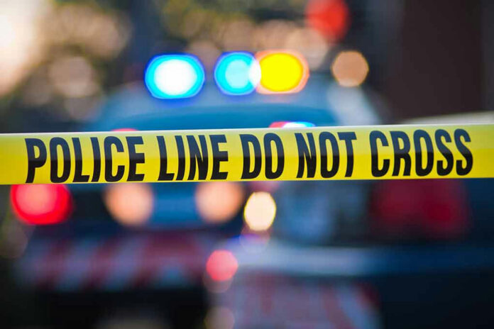 56280433 Police tape with flashing lights in background.