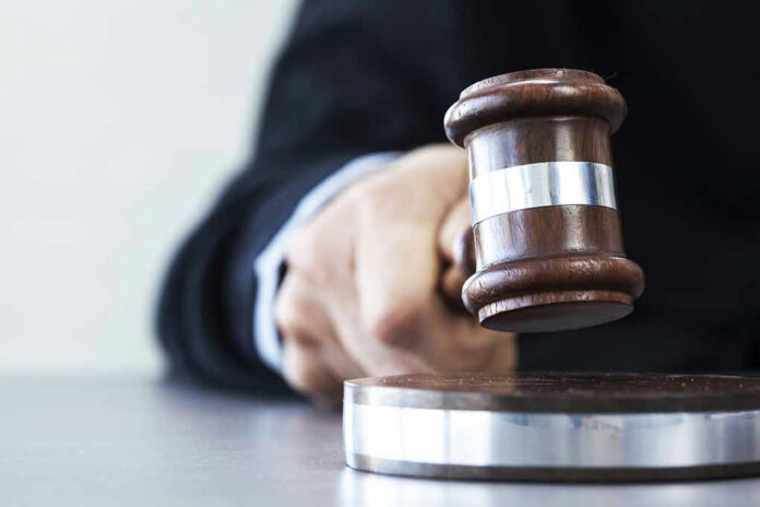 565403683 Judges hand hitting gavel on block.
