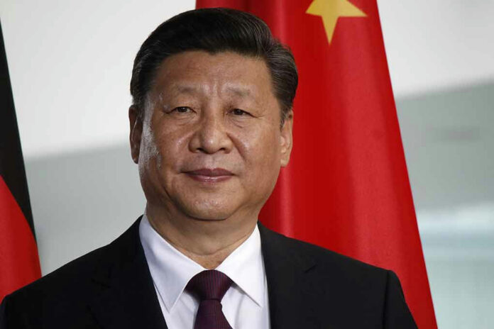 677148799 Man in suit standing before Chinese flag.