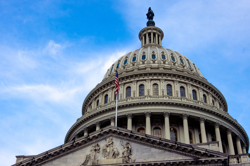Low,Angle,View,Of,American,Flag,On,United,States,Capitol View of the U.S. Capitol building dome against a blue sky