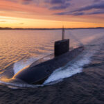 A submarine navigating through the ocean during sunset
