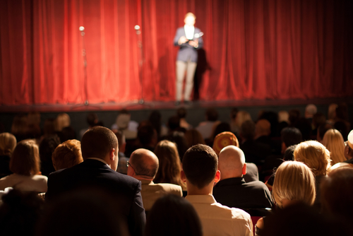 Audience watching a speaker on stage in a theater