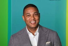 Media Star Labels MAGA Nazis — With a Catch smiling man in gray suit against teal background