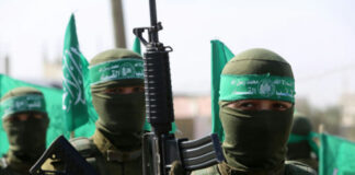 Militants in uniforms and masks holding green flags and guns.