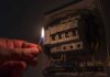 Power Prices EXPLODE — Blackouts Hit hand holding a lit match near an electrical breaker panel