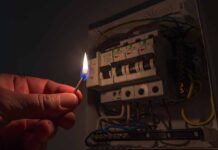 Power Prices EXPLODE — Blackouts Hit hand holding a lit match near an electrical breaker panel
