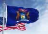 Michigan Meltdown Threatens Dem Hopes United States and Michigan flags waving against blue sky.