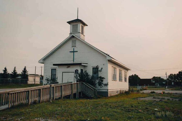 Small white church with steeple and cross at sunset