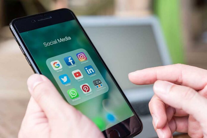 Person holding smartphone with social media app folder open