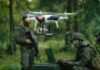 $400 Drones Humiliate Million-Dollar Tanks Soldiers in a forest operating a drone.