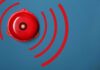 Red alarm bell with sound waves illustration.