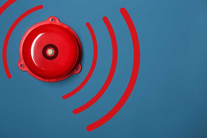 Red alarm bell with sound waves illustration.