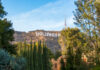 Hollywood Sign on hillside surrounded by trees, clear sky.