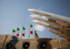 Missiles on launchers beside Iranian flags.