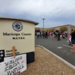 Protest outside Maricopa County elections building with signs.