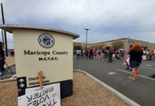 Protest outside Maricopa County elections building with signs.