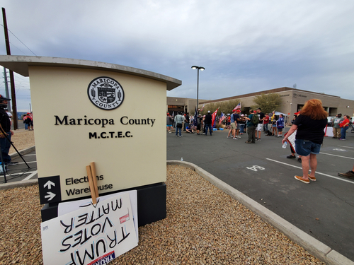 Protest outside Maricopa County elections building with signs.