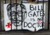 Sign saying Bill Gates is no doctor on a gate.