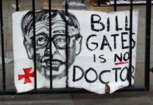 Sign saying Bill Gates is no doctor on a gate.