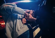 Person being handcuffed by police officer at night.